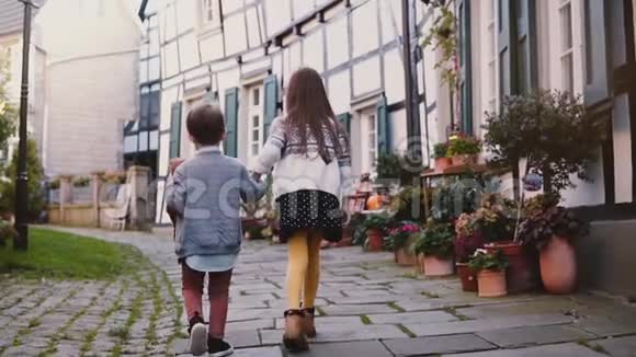 两个小孩子一起沿着旧建筑走女孩和男孩探索美丽的德国古镇团结友爱视频的预览图