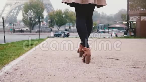 年轻快乐的女人在雾天走在市中心靠近法国巴黎的埃菲尔铁塔使用智能手机视频的预览图