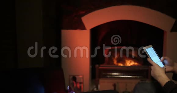 胡须男用平板电脑靠近壁炉滑动视频的预览图