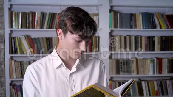 布鲁内特曼正在看书在镜头前看在后台看图书馆视频的预览图