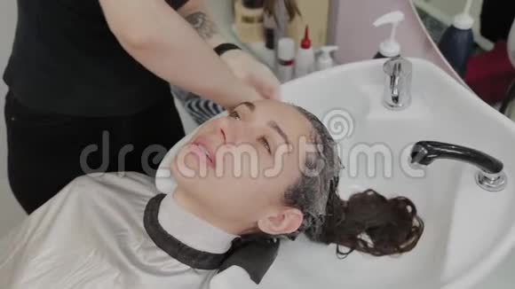 女理发师把洗发水放在客户的头上视频的预览图