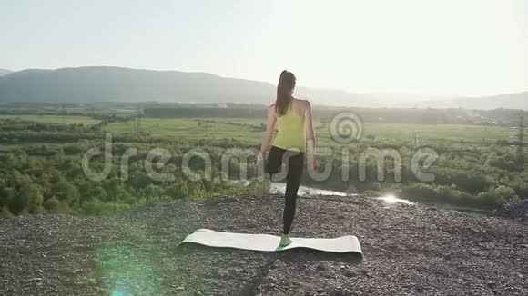 这个运动女孩在户外做瑜伽练习侧视苗条的金发女孩站在瑜伽姿势上视频的预览图