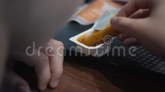 这个男孩正在咖啡馆里吃快餐一个孩子吃带有酱汁和番茄酱的金块视频的预览图