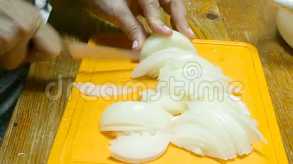厨师用刀切洋葱在橙色的切割板上视频的预览图