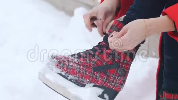 冬季一个女人把鞋带系在鲜红的溜冰鞋上视频的预览图