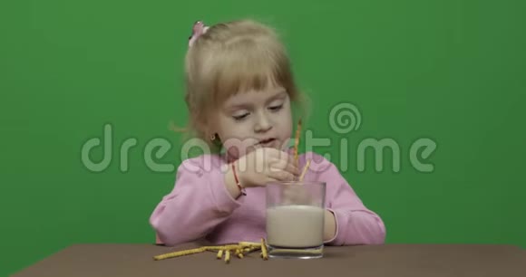 孩子吃饼干一个小女孩坐在桌子上吃饼干视频的预览图