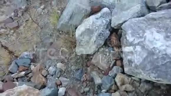 一个人走在山上的岩石上拍摄了一段视频其中有雪山和冰川在底部视频的预览图