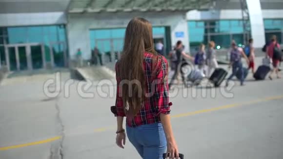 年轻男子步行到现代机场候机楼为她的航班从后面看女性旅行者视频的预览图