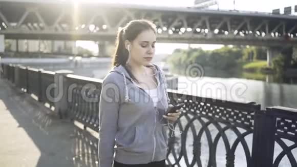冷静的黑发女人带着她的智能手机沿着莫斯科河散步视频的预览图