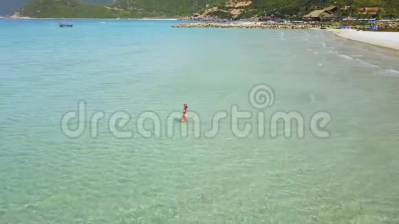 快乐的女人穿着比基尼在夏天的海滩上享受清澈的海水从飞行无人机的鸟瞰透明的女人视频的预览图
