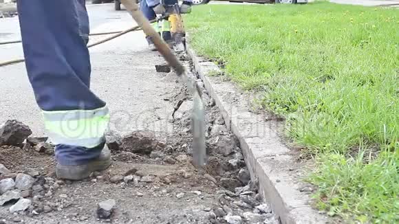 一个拿着铁锹的工人在挖土机后面收集破碎的沥青视频的预览图