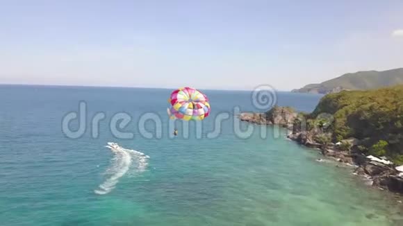 空中观景伞飞过碧海拉船在海湾和绿岛景观无人驾驶飞机景观中飞行视频的预览图