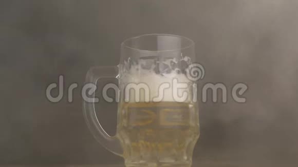 扭曲的啤酒杯里面倒入新鲜啤酒烟雾新鲜特写黑色背景慢动作凉爽视频的预览图