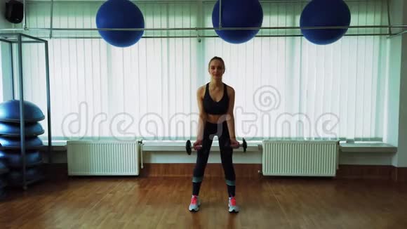 年轻女孩在健身房用哑铃做运动视频的预览图