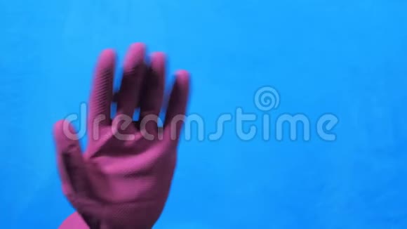 干净的手在蓝色背景上的紫色橡胶手套手挥手说再见的手势视频的预览图