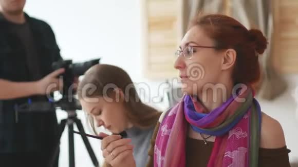 录像师在摄影棚里向摄影艺术家拍摄视频的预览图