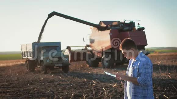 农民在耕地上使用数字平板电脑背景中的拖拉机概念现代技术视频的预览图