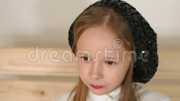 一个戴着黑色老式帽子的小女孩在工作室里摆着白色背景视频的预览图