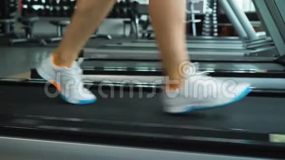 女子在健身房跑步机上跑步的特写镜头视频的预览图