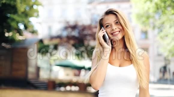 漂亮的女人在她的手机上说话而她走着美丽的欧洲街道城里散步的年轻快乐女孩视频的预览图