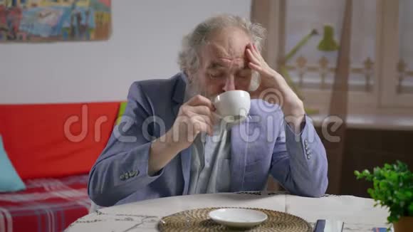 抑郁胡子企业家西装在舒适的公寓喝茶的肖像视频的预览图