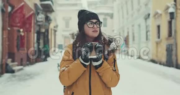 美丽的少女喝着咖啡环顾白雪皑皑的冬城视频的预览图