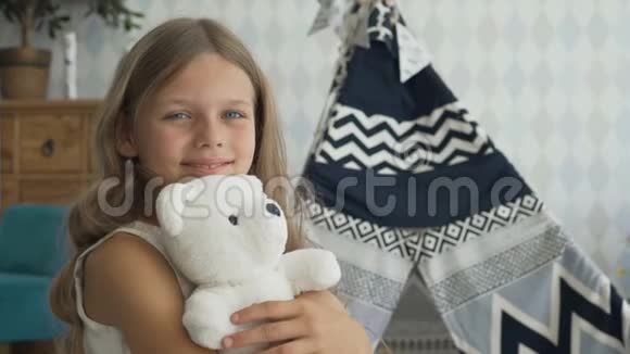 可爱的女孩正抱着一只白色的泰迪熊看着相机微笑着视频的预览图
