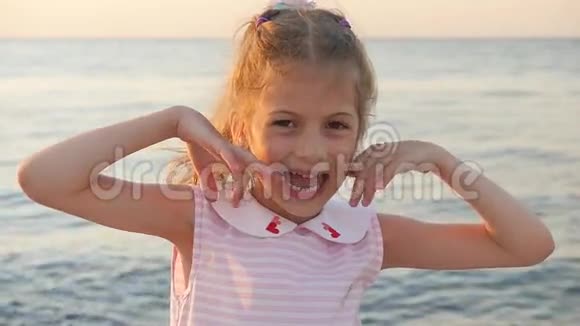 美丽的小女孩鬼脸在夕阳的海面上露出舌头视频的预览图