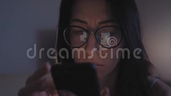一位戴眼镜的女士坐在沙发上用智能手机进行网上购物网上营销视频的预览图