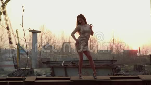美丽的女人在夕阳下跳舞站在金属建筑上视频的预览图