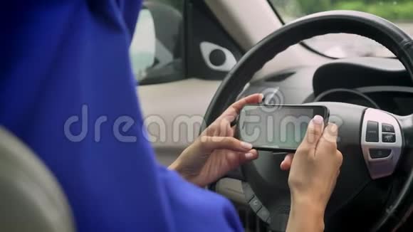 戴头巾的女人在自动驾驶自动驾驶无人驾驶汽车的自动驾驶方向盘后面打电话发短信视频的预览图