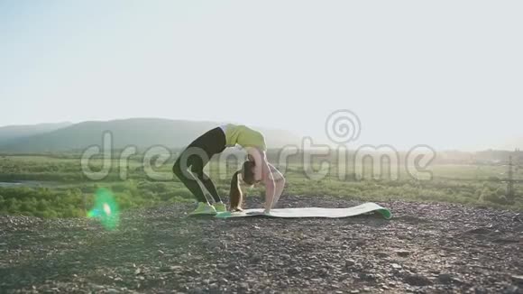 瑜伽体操女孩在森林附近的河流背景下在山顶进行运动训练灵活性练习视频的预览图