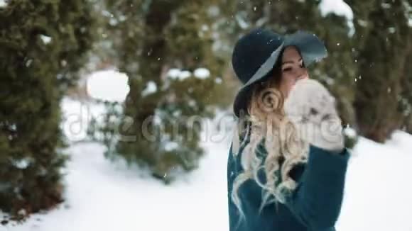 穿着绿帽子和绿衣的女士在森林里飘落的雪下旋转视频的预览图