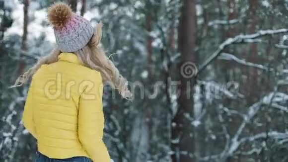 穿着黄色夹克的漂亮年轻女子在冬天的森林里奔跑视频的预览图