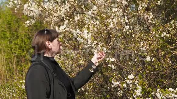 一棵开花的树附近的年轻女子视频的预览图