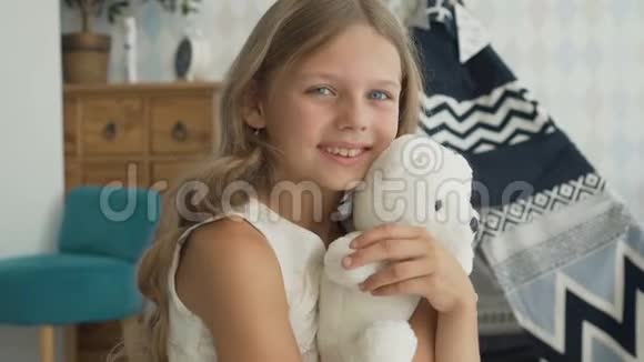 可爱的小女孩正抱着一只玩具熊看着相机微笑着视频的预览图
