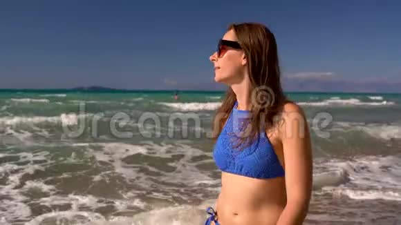 海滩比基尼女人无忧无虑地沿着海滩上的水走希腊科孚美丽的海岸视频的预览图