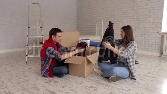 一对快乐的夫妇在他的新公寓里坐在地板上拆箱视频的预览图