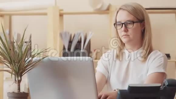 在办公室用电脑工作的女人拿起电话视频的预览图
