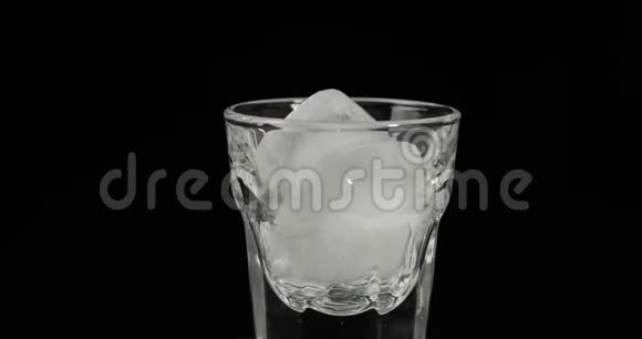 将伏特加倒入装有冰块的杯中置于黑色背景下视频的预览图