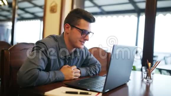积极微笑的白种人戴着眼镜在视频电话会议上交谈在咖啡馆里用笔记本电脑聊天议长视频的预览图