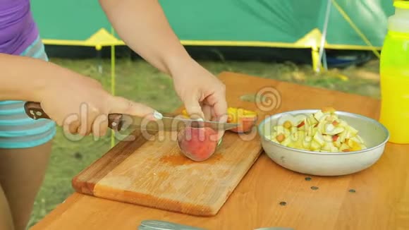 一个年轻的女人用刀把一个桃子从石头上洗掉视频的预览图