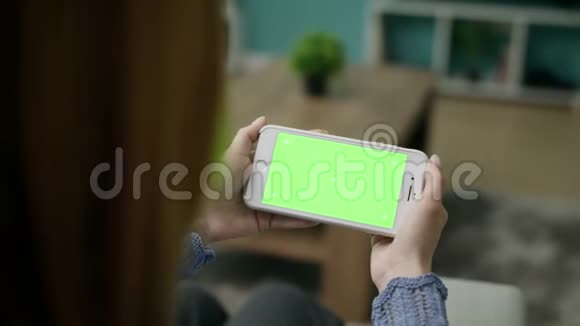 女人在家用绿色锁屏智能手机在沙发上唱歌视频的预览图