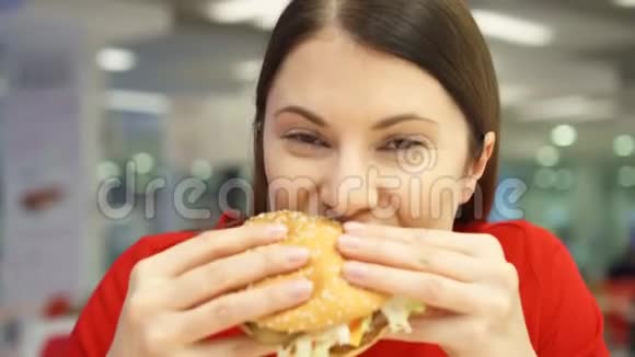 非常饥饿的女孩在食物场上吃汉堡包快餐店的女人咬芝士汉堡视频的预览图