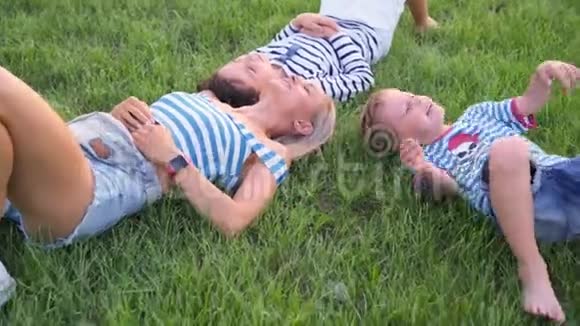 家庭生活方式的场景母亲和儿子一起在公园的绿草上休息视频的预览图