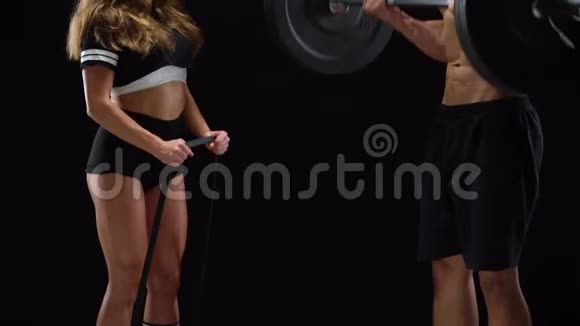 运动的男人和女人用哑铃和杠铃弯曲他们的手在黑色的背景上训练他们的二头肌视频的预览图