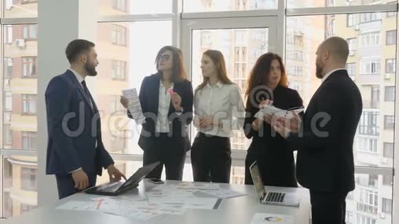 办公室工作人员一家大公司的雇员两名年轻男子和三名年轻妇女站在桌子旁拿着文件视频的预览图