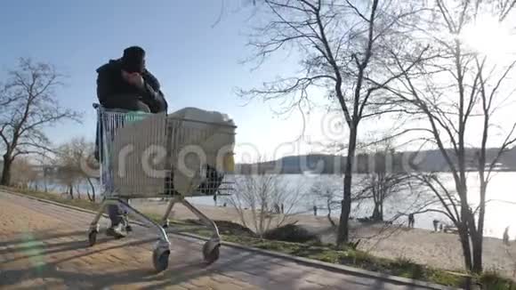 无家可归的成熟男人推着手推车的正面景色视频的预览图