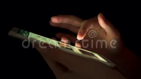 夜间在室内使用智能手机触摸屏的女性手部特写浏览信使视频的预览图