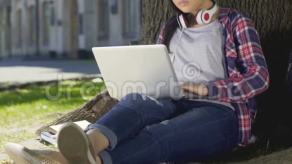 混合种族的学生坐在笔记本电脑露天做毕业设计视频的预览图